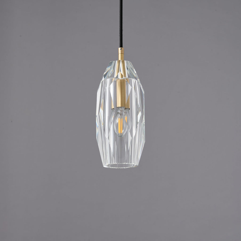 A Clérachic pendant with a faceted clear glass shade around a brass lamp holder, unlit on a grey backdrop.