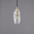 A Clérachic pendant with a faceted clear glass shade around a brass lamp holder, unlit on a grey backdrop.