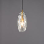 The faceted clear glass Clérachic pendant lit, with the filament bulb glowing through the cut glass.