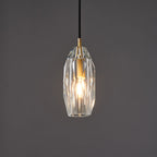 The faceted glass Clérachic pendant lit warm against a darker grey backdrop, with light playing across the cut facets.
