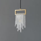 A Clérachic pendant with a frosted, icicle-like glass drape over a brass rectangular frame, unlit on grey.