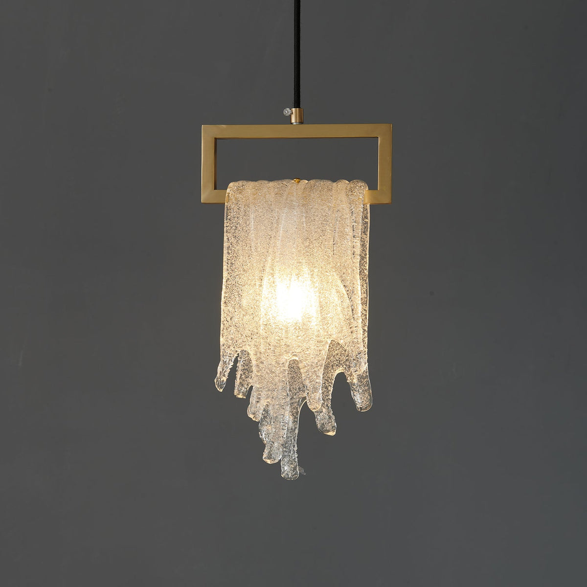 A close view of the lit draped glass Clérachic pendant, with a bright centre and a textured, sparkling glass surface.