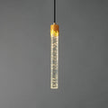 The bubble-glass rod Clérachic pendant lit, with tiny points of light in the clear glass below the brass cap.