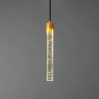 The bubble-glass rod Clérachic pendant lit, with tiny points of light in the clear glass below the brass cap.