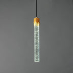 The lit bubble-glass rod Clérachic pendant with a cool, slightly green-white glow along the clear glass.