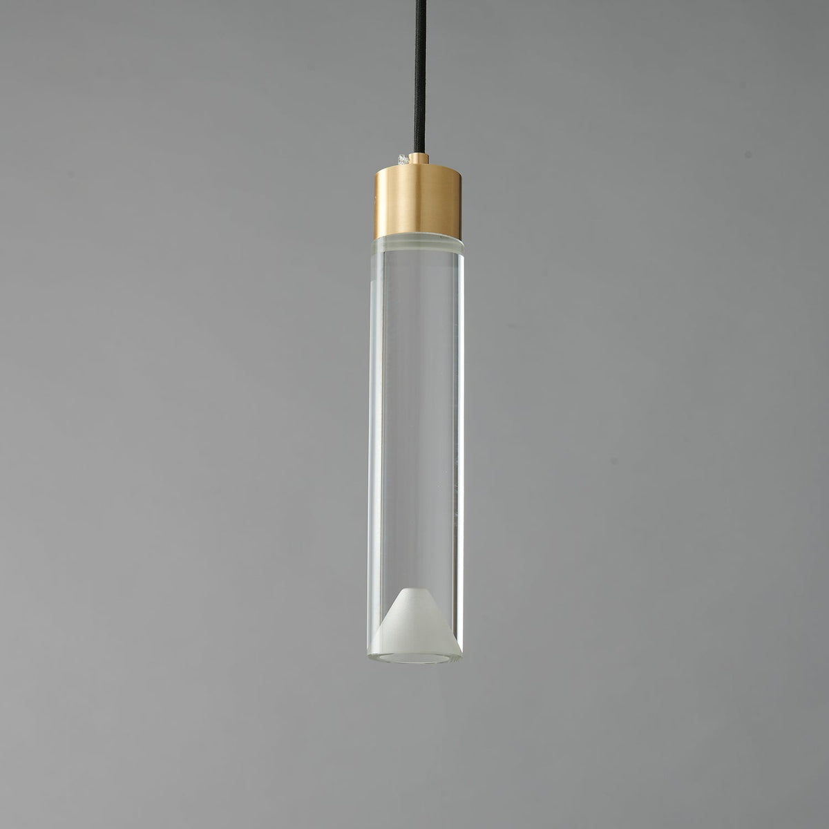 A Clérachic pendant with a long clear glass cylinder, a brass cap and a frosted cone at its base, unlit on grey.
