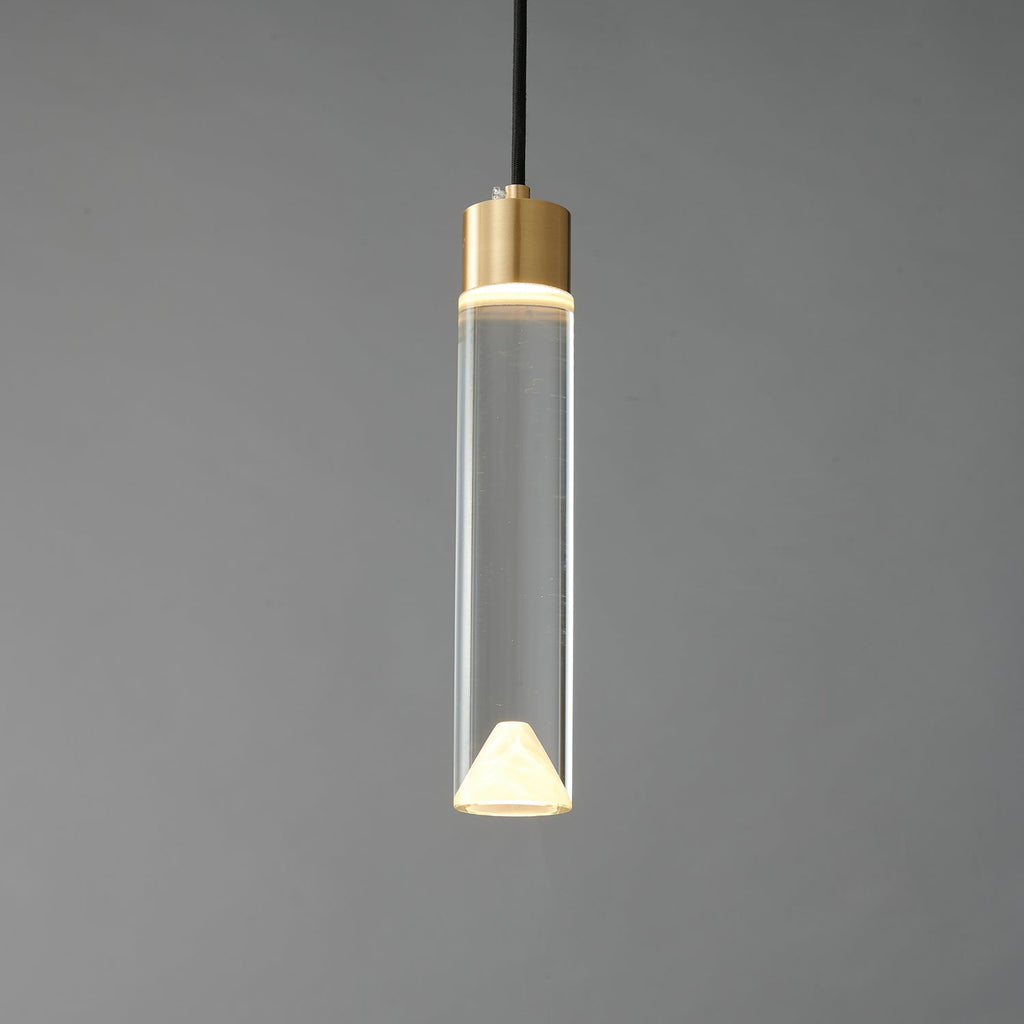 The glass cylinder Clérachic pendant lit, with a bright ring at the brass cap and a glowing cone at the base.