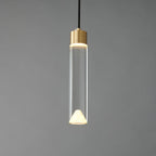 The glass cylinder Clérachic pendant lit, with a bright ring at the brass cap and a glowing cone at the base.