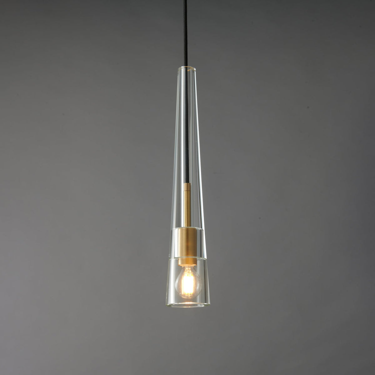 The tapered clear glass Clérachic pendant lit, with a warm filament bulb inside the glass cone.