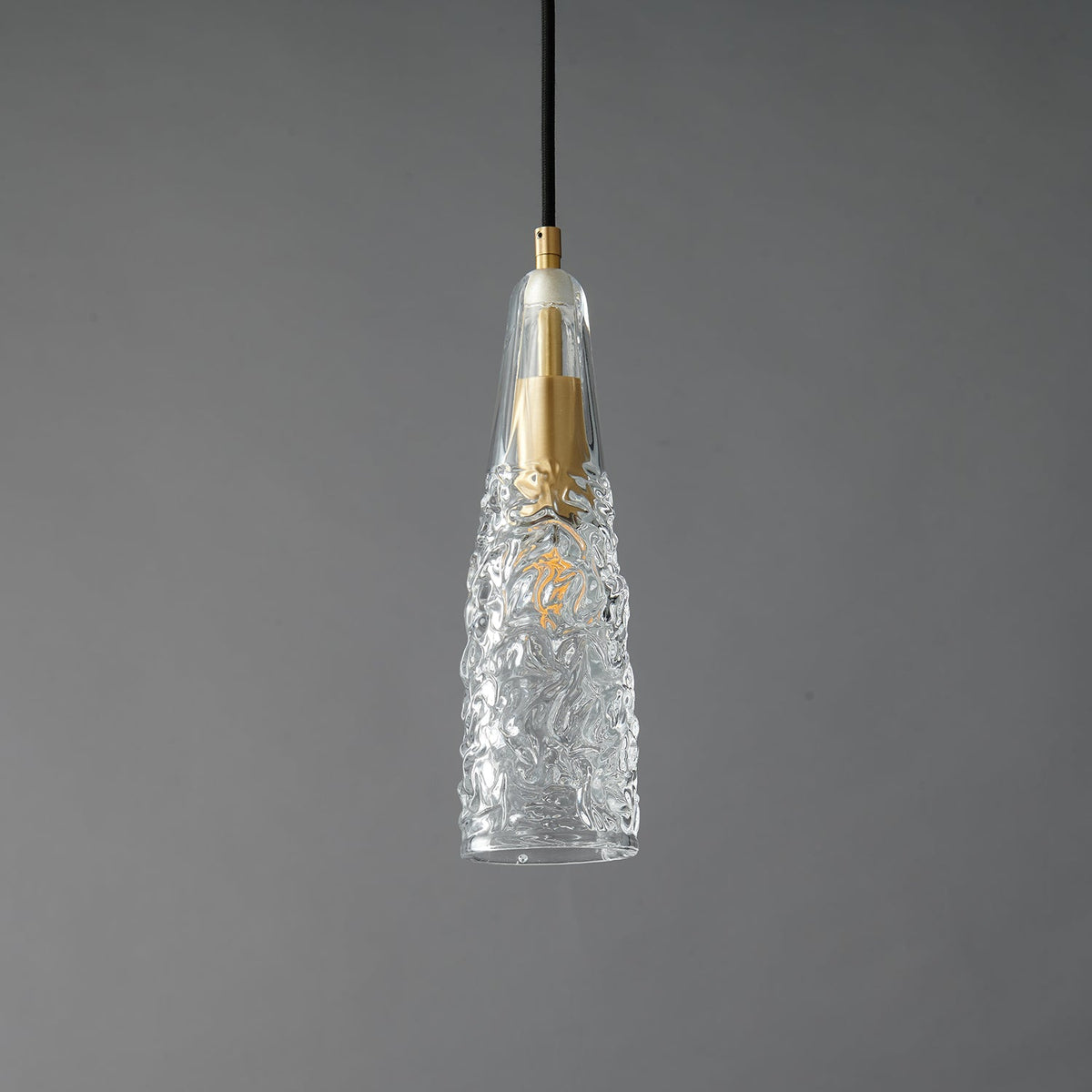 A Clérachic pendant with a crinkled, ice-textured clear glass shade tapering to a point around a brass fitting.