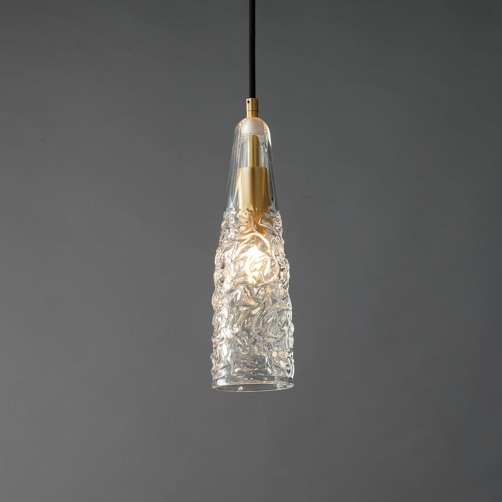 Close view of the lit crinkled glass Clérachic pendant, with the bulb glowing through the textured clear shade.