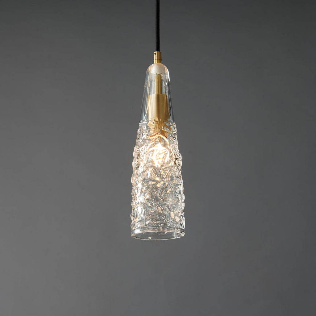A lit Clérachic pendant with a crinkled glass shade, with a bright bulb glow inside and a brass fitting at the top.