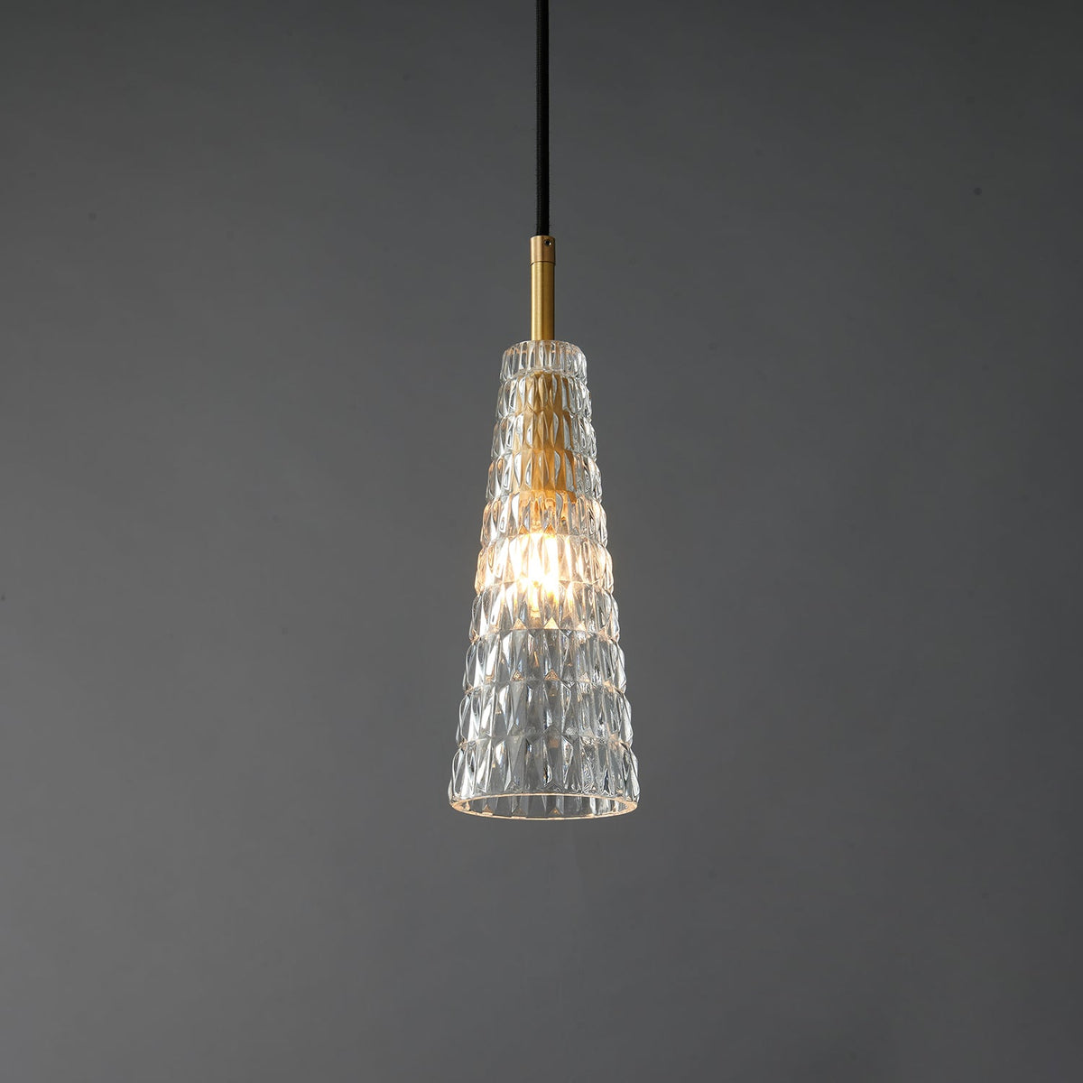 The diamond-patterned tapered Clérachic pendant lit, with the filament bulb glowing inside the moulded glass.