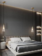 A taller view of a bedroom with two textured clear glass Clérachic pendants hanging on either side of the bed.