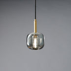 The rounded smoke grey Clérachic pendant lit, with a bright bulb glowing inside the tinted glass.