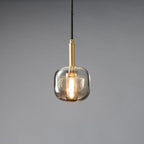 A rounded smoke grey Clérachic pendant lit warm, with a brass stem and black cord on a grey backdrop.