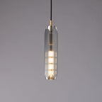 A tall, slim Clérachic pendant with a smoke grey glass shade, lit from within by a long filament bulb, on a grey backdrop.