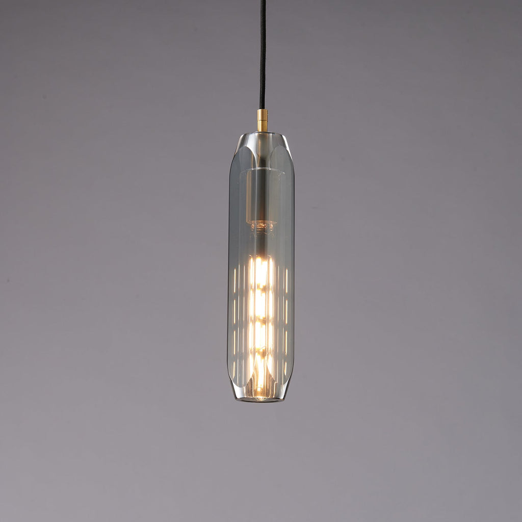 The slim smoke grey Clérachic pendant lit, with a stack of glowing filament segments visible through the glass.