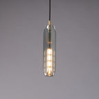 The slim smoke grey Clérachic pendant lit, with a stack of glowing filament segments visible through the glass.