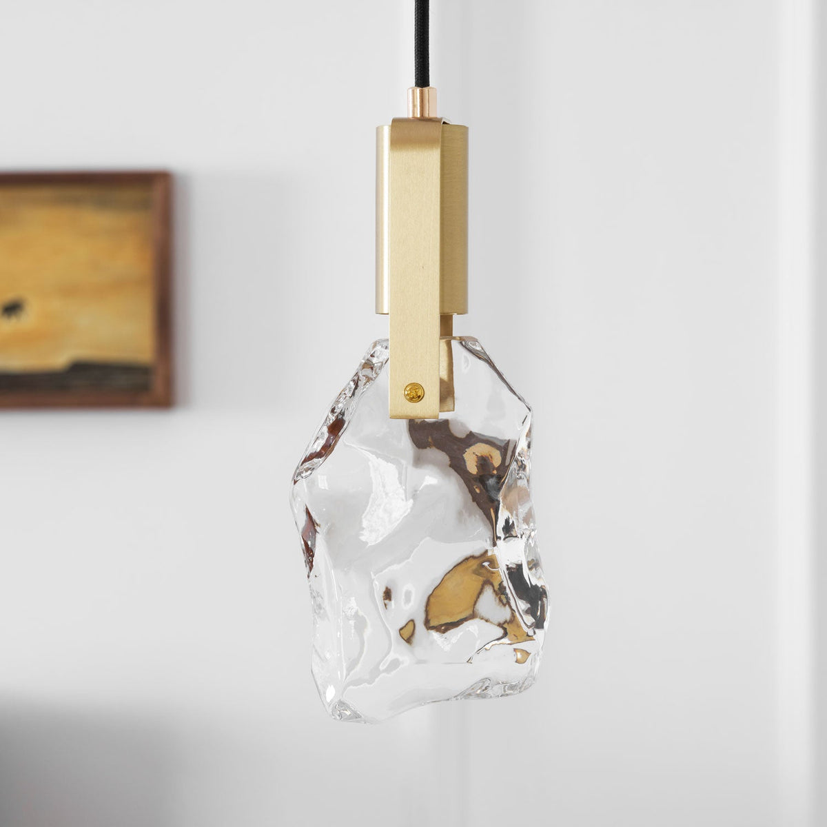Close view of the rough, faceted clear glass and square brass bracket on this Clérachic pendant.