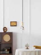 The rock-glass Clérachic pendant hangs on a white panelled wall with a cane-fronted cabinet and a small painting beside it.
