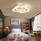 Clérachic cloud-shaped ceiling light with hanging white stars over a child's bedroom with green walls, a desk and a bookcase.