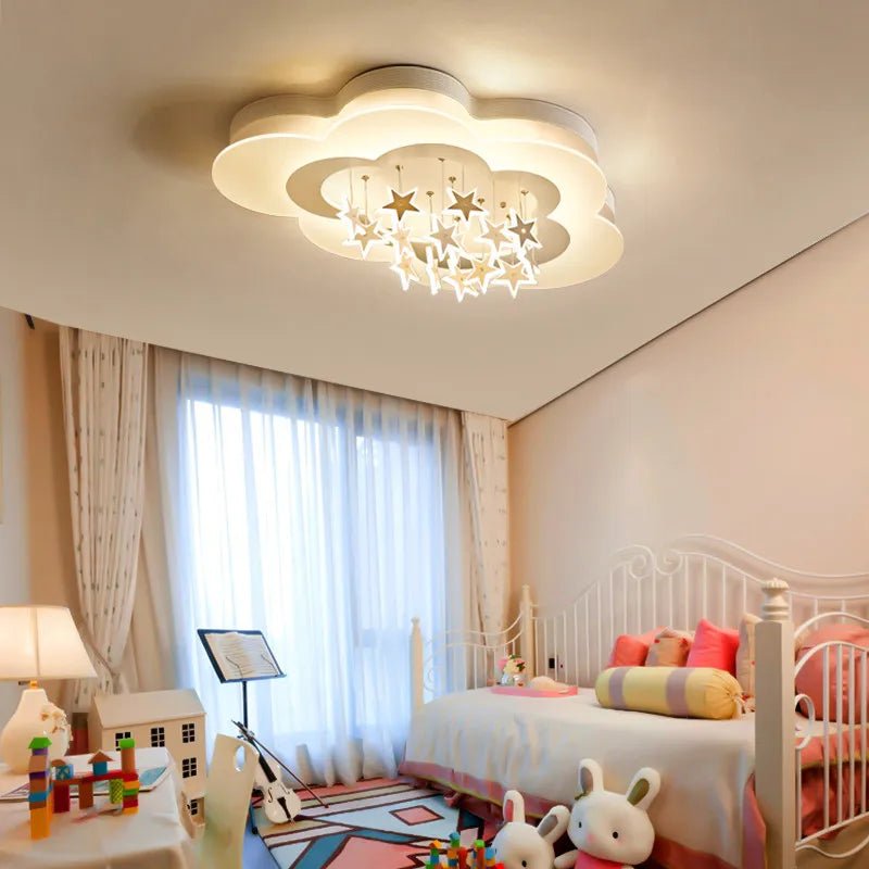 Clérachic white cloud-shaped ceiling light with dangling stars in a bright nursery room with sheer curtains and soft toys.