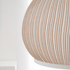 Clérachic knit pendant lamp in macro across the shoulder of the shade, rust and grey threads running down the white rib to the ring.