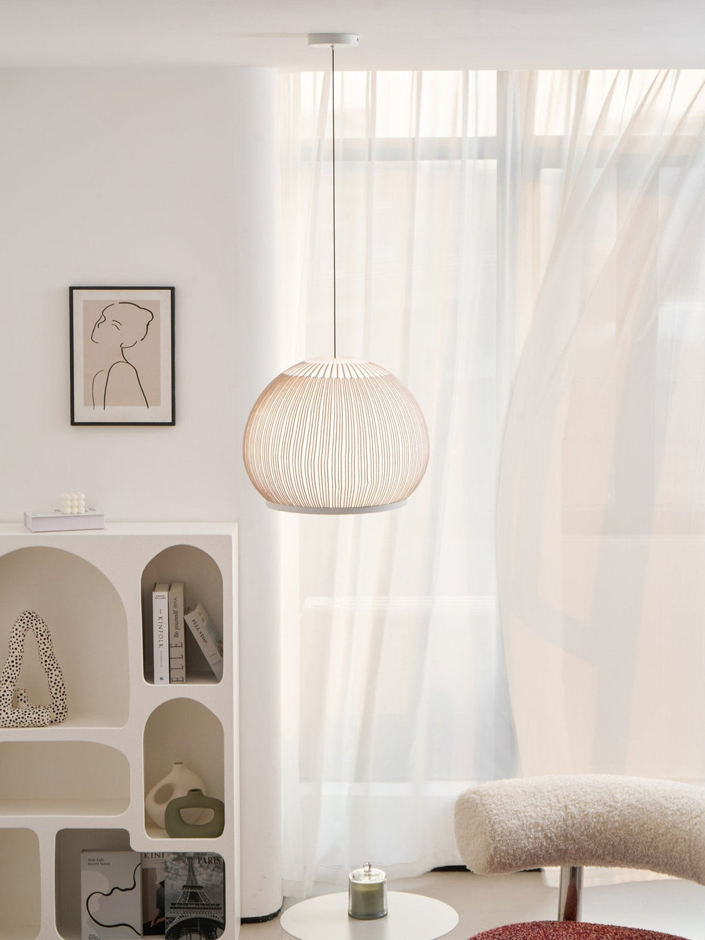 Clérachic round globe knit pendant lamp with sunlight breaking through the sheer curtain behind, the canopy and cord above it.