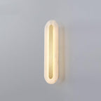 The Clérachic Kristy wall lamp mid-size on grey, a soft halo spreading behind the stone.