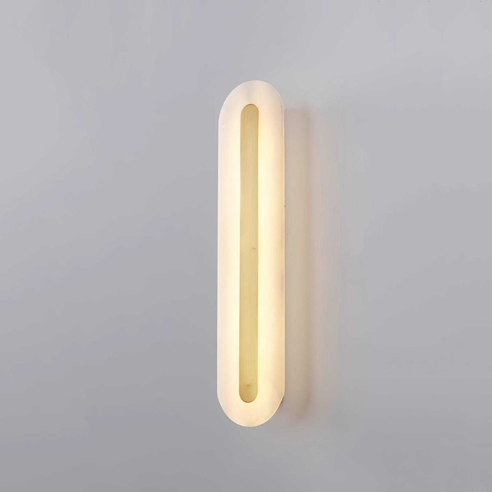 Clérachic Kristy wall lamp lit on grey, brass bar running the length of the alabaster.