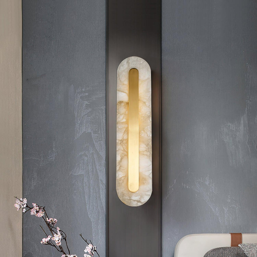 Clérachic Kristy wall lamp lit on a slate wall beside a branch of cherry blossom.
