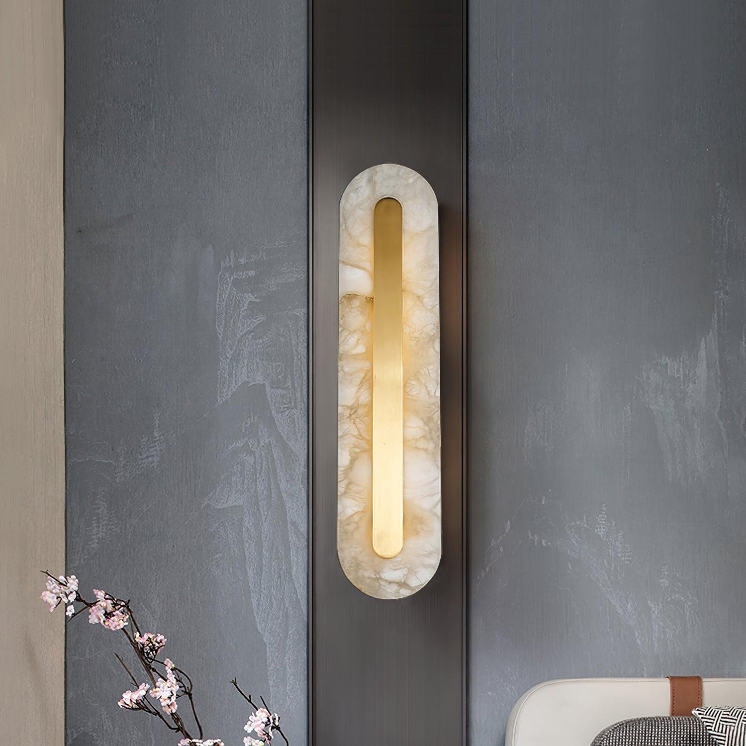 Clérachic Kristy wall lamp lit on a slate wall beside a branch of cherry blossom.