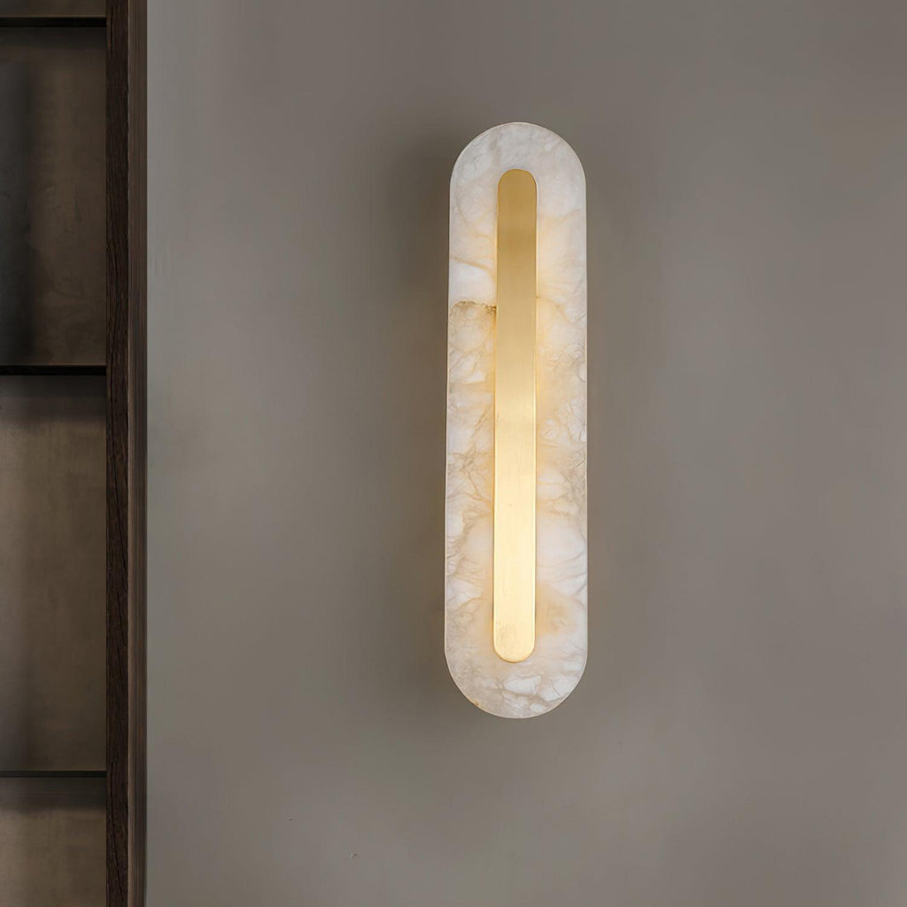 The Clérachic Kristy wall lamp glowing on a bronze panel beside a tall mirror.