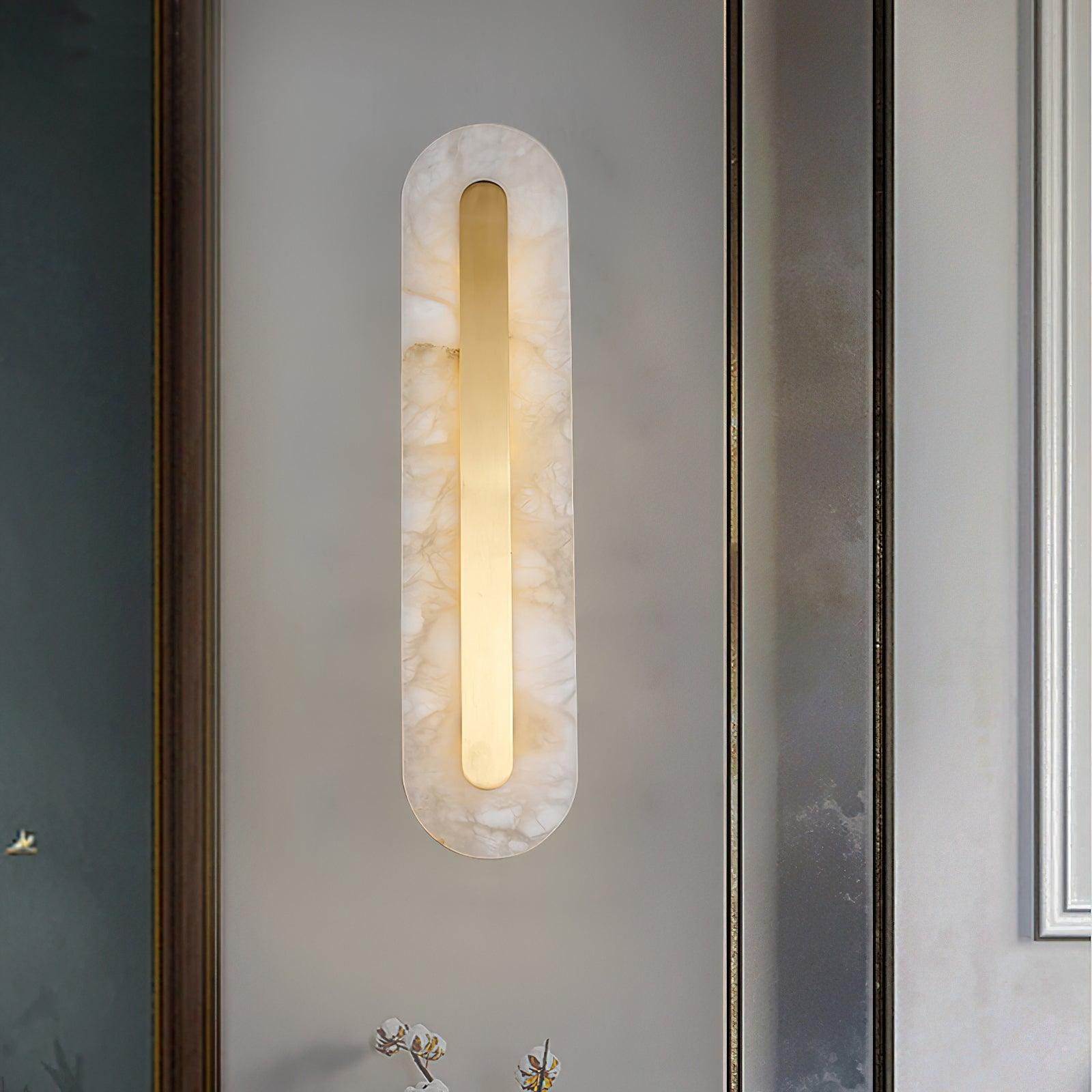 Clérachic Kristy wall lamp on a pale wall between a framed picture and a mirrored panel.