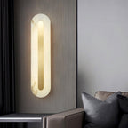 Clérachic Kristy wall lamp lit on grey beside a leather sofa and dark cushions.