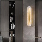 The Clérachic Kristy wall lamp on a concrete-look door panel beside dark shelving.