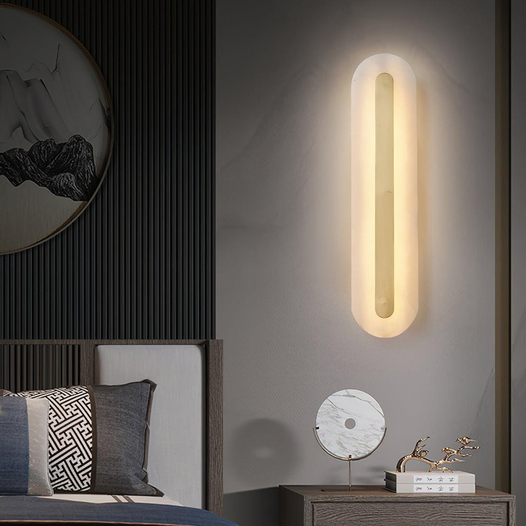Clérachic Kristy wall lamp lit beside a bed with a round mirror and ribbed panelling.