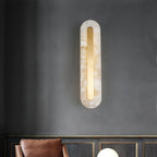 Clérachic Kristy wall lamp lit on charcoal plaster above a tan leather chair.