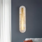Clérachic Kristy wall lamp on a slate-blue wall beside sheer curtains and a bed.