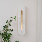 The Clérachic Kristy wall lamp unlit on cream, a leafy branch crossing the lower frame.