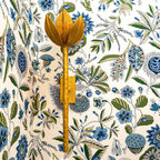 The Clérachic brass tulip sconce sits on a wood mounting block against blue floral wallpaper.