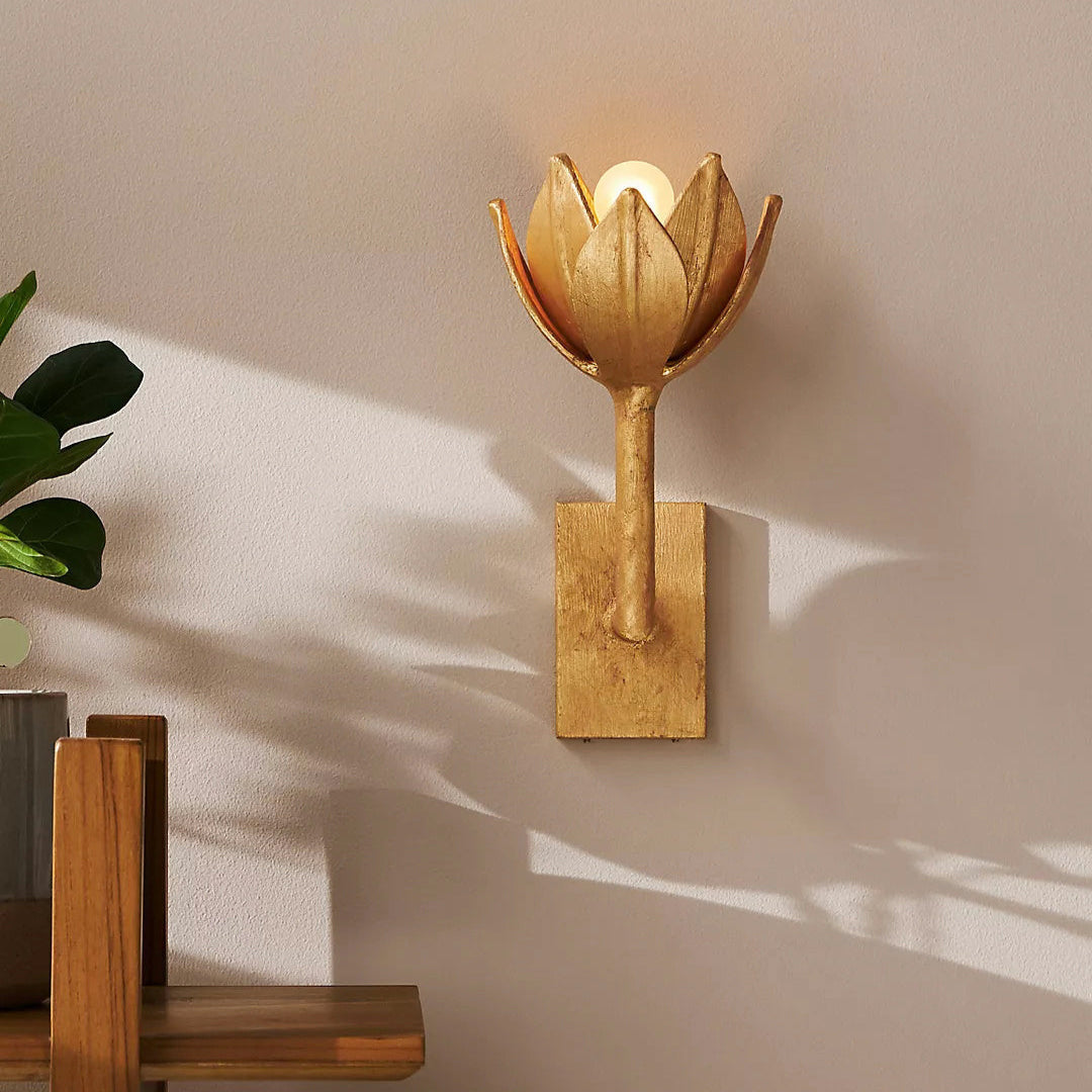 The Clérachic brass tulip sconce casts warm light and long shadows across a beige bedroom wall.