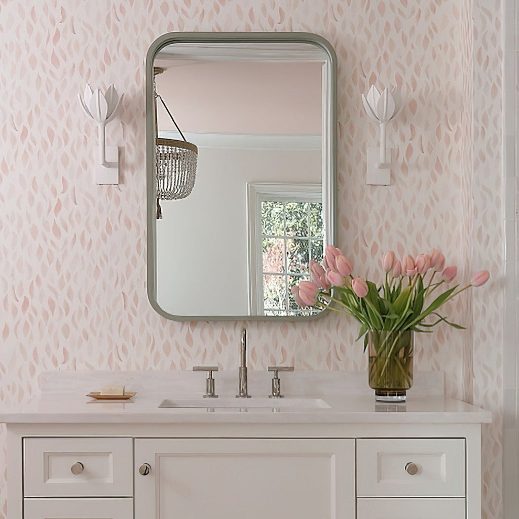 The Clérachic white tulip sconces flank a mirror in a blush bathroom with leaf-print wallpaper.