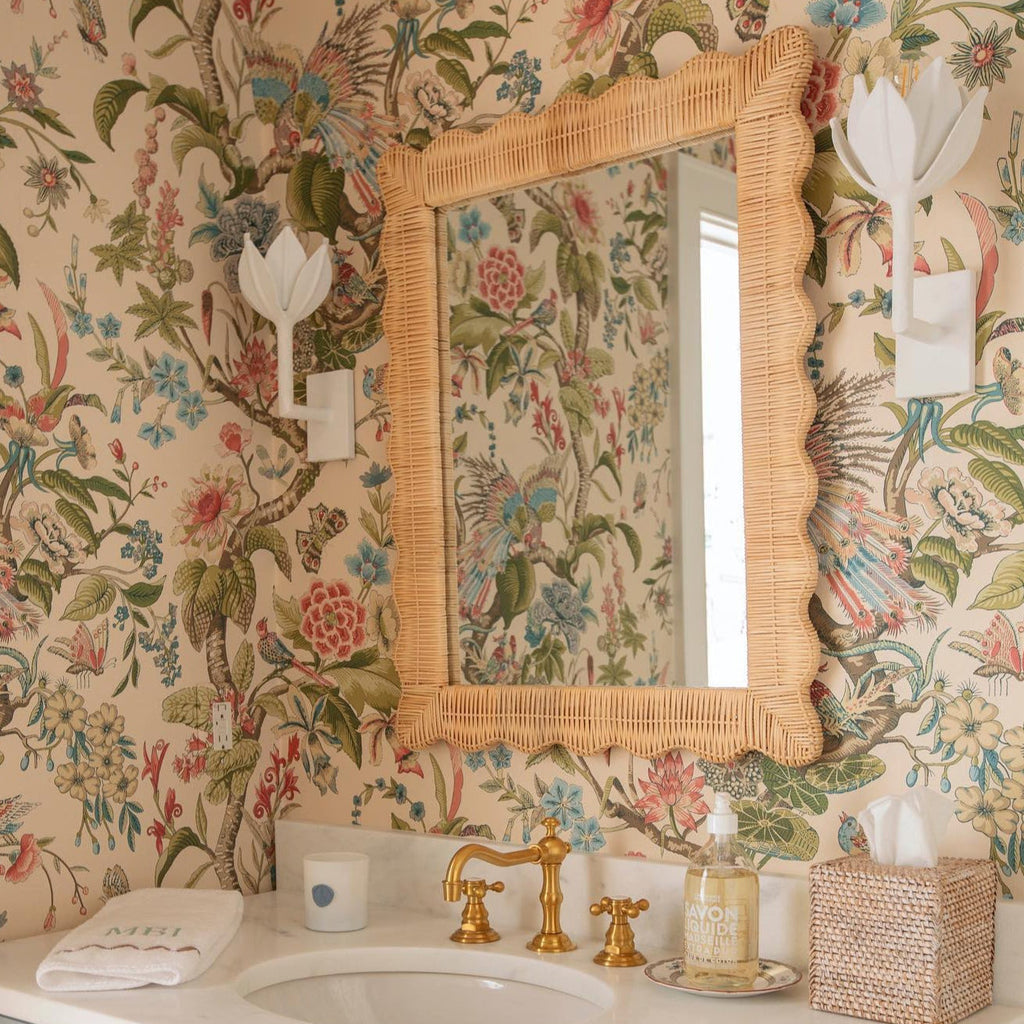 The Clérachic white tulip sconces flank a rattan mirror in a warm floral wallpapered bathroom.
