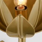 The Clérachic sconce shows its glowing filament bulb seated inside brass petal walls.
