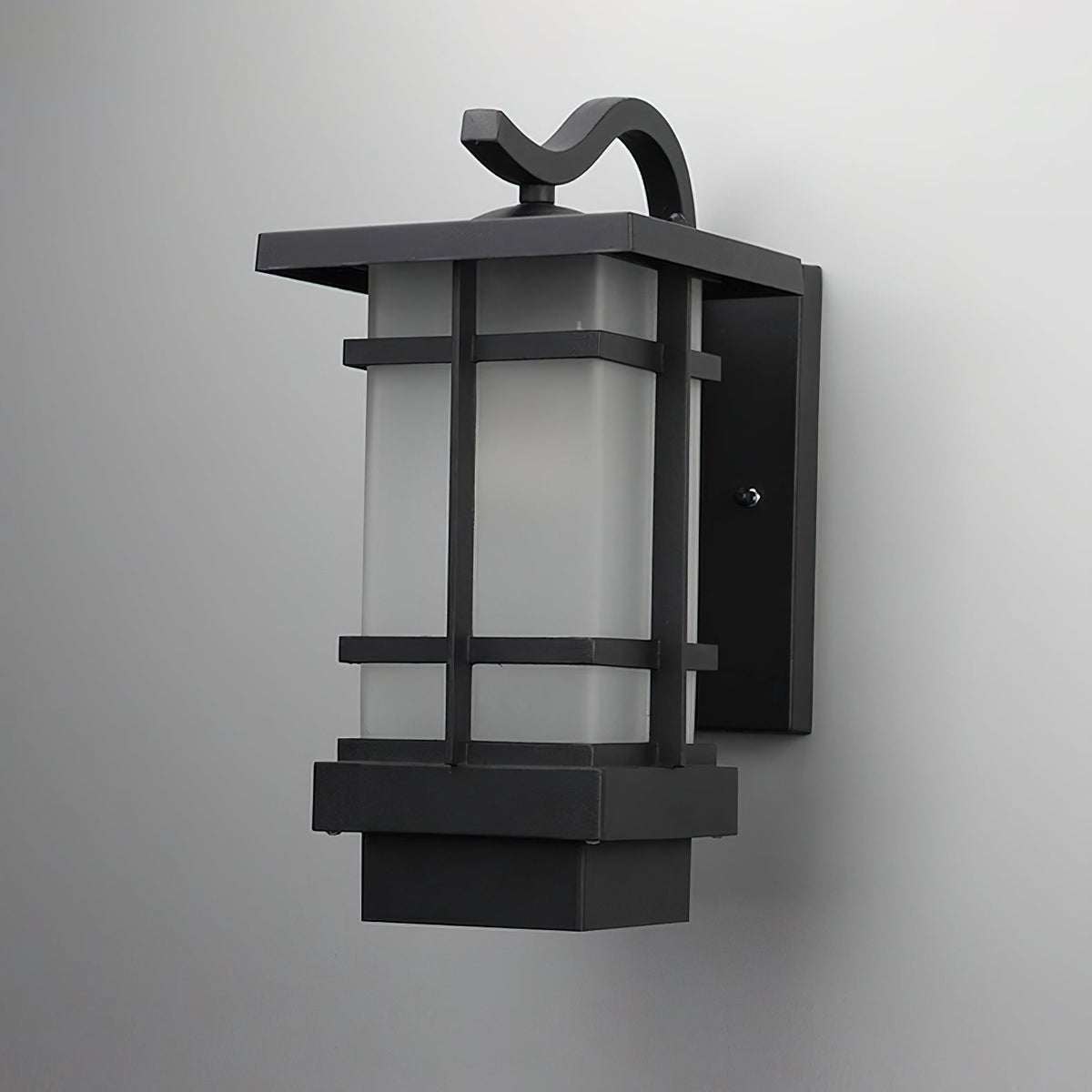 Wall-mounted Clérachic lantern in black aluminium, shown close up against a grey wall, its frosted glass in a grid frame.