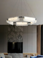 Clérachic Layered Alabaster Plate Chandelier lighting a living room above a marble media wall and blue velvet seating.