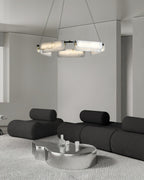 Clérachic Layered Alabaster Plate Chandelier over a black modular sofa and chrome table in a pale minimalist room.