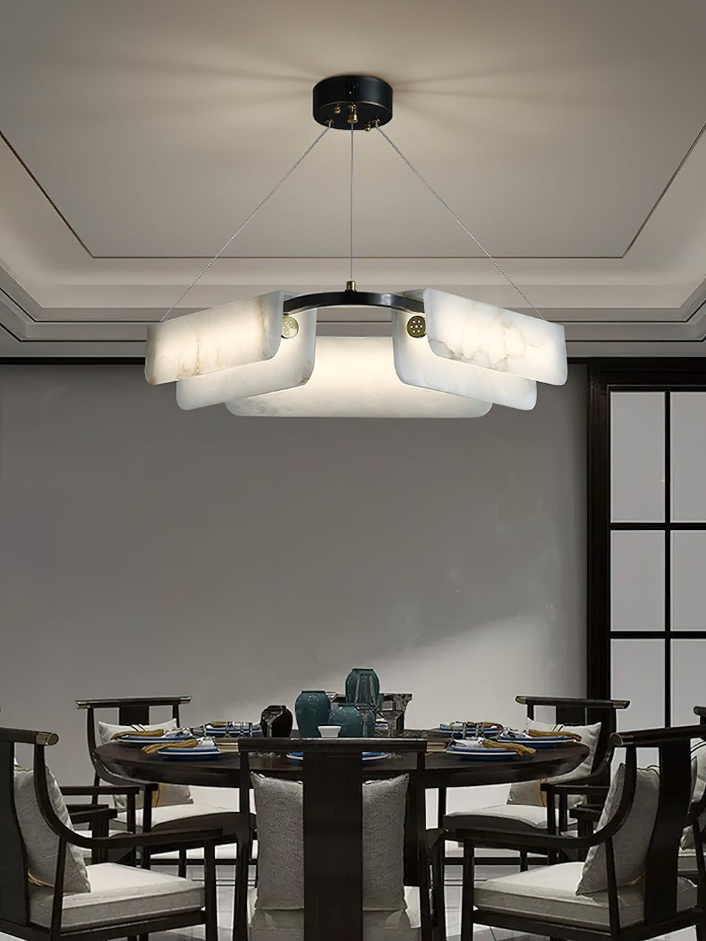 The Clérachic Layered Alabaster Plate Chandelier centred over a round dining table set for a family meal.
